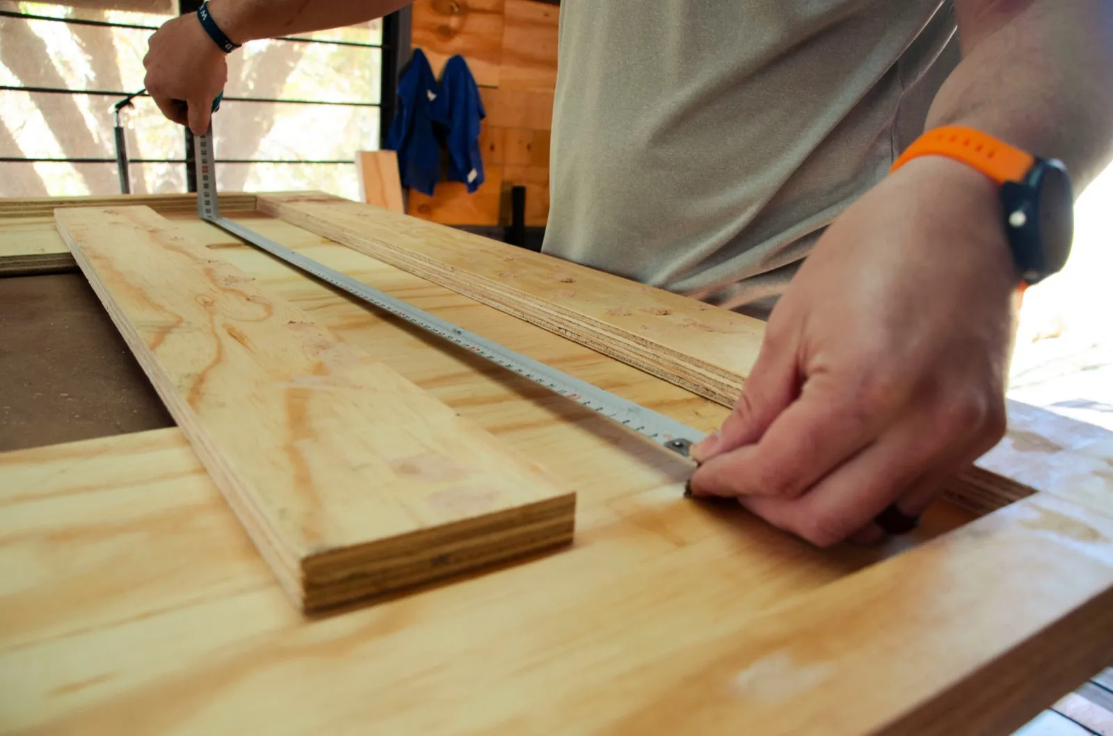 Hands measuring a board with a tape measure